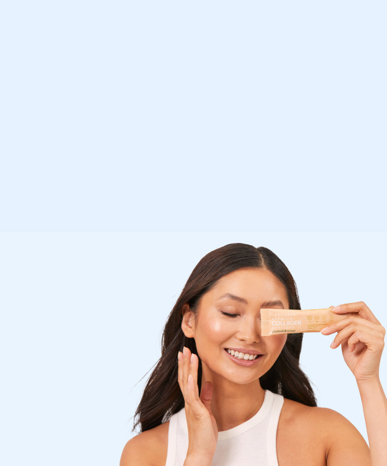 Smiling woman holding collagen supplement sachet, wearing a white tank top. Light blue background enhances the beauty and skincare theme.