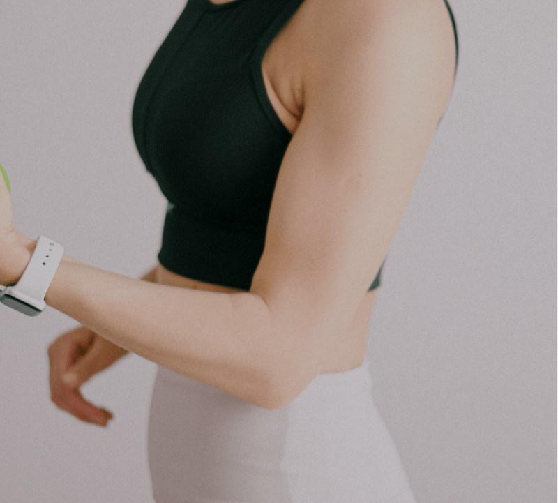 Woman in activewear holding a container, suggesting a focus on beauty supplements like collagen. Her smartwatch accents her fitness theme.
