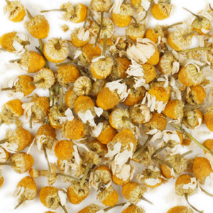 Pile of dried chamomile flowers with yellow centers and white petals, used for natural beauty and wellness supplements.