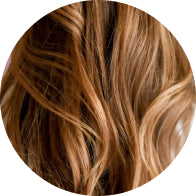 Close-up of wavy, golden brown hair, highlighting smooth texture and shine. Perfect for beauty and haircare focus.