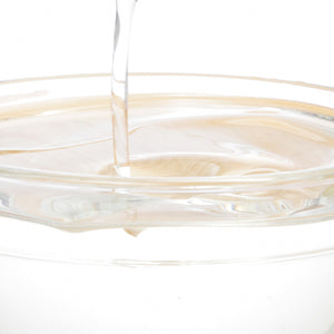 Clear liquid collagen pouring into a glass container, emphasizing beauty and skincare supplements.