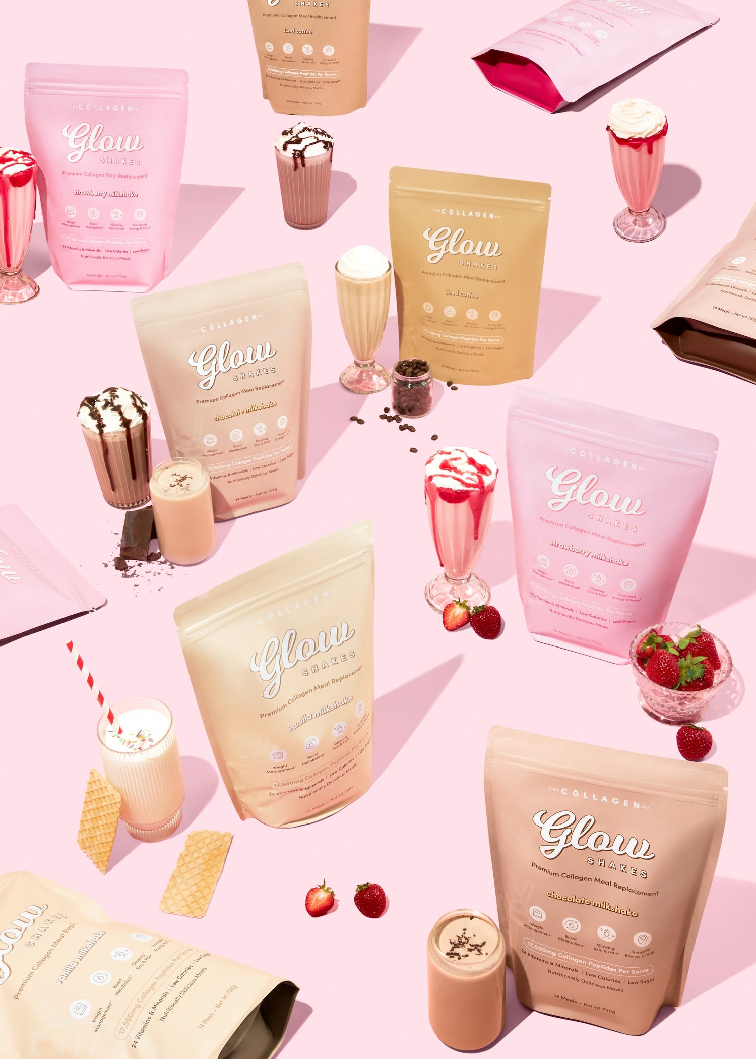 Assorted collagen supplement bags and milkshakes on a pink surface, featuring fruits and wafers.