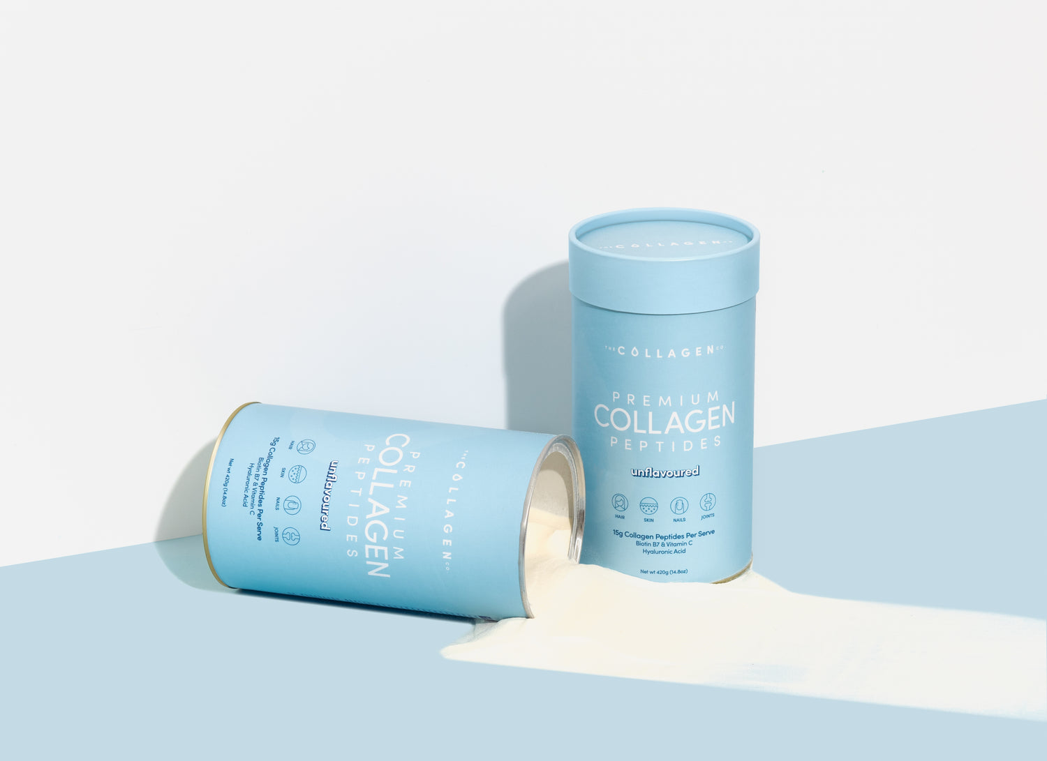 Two blue containers of collagen peptides; one upright, one tipped with powder spilling out. Minimalist design on a light background.
