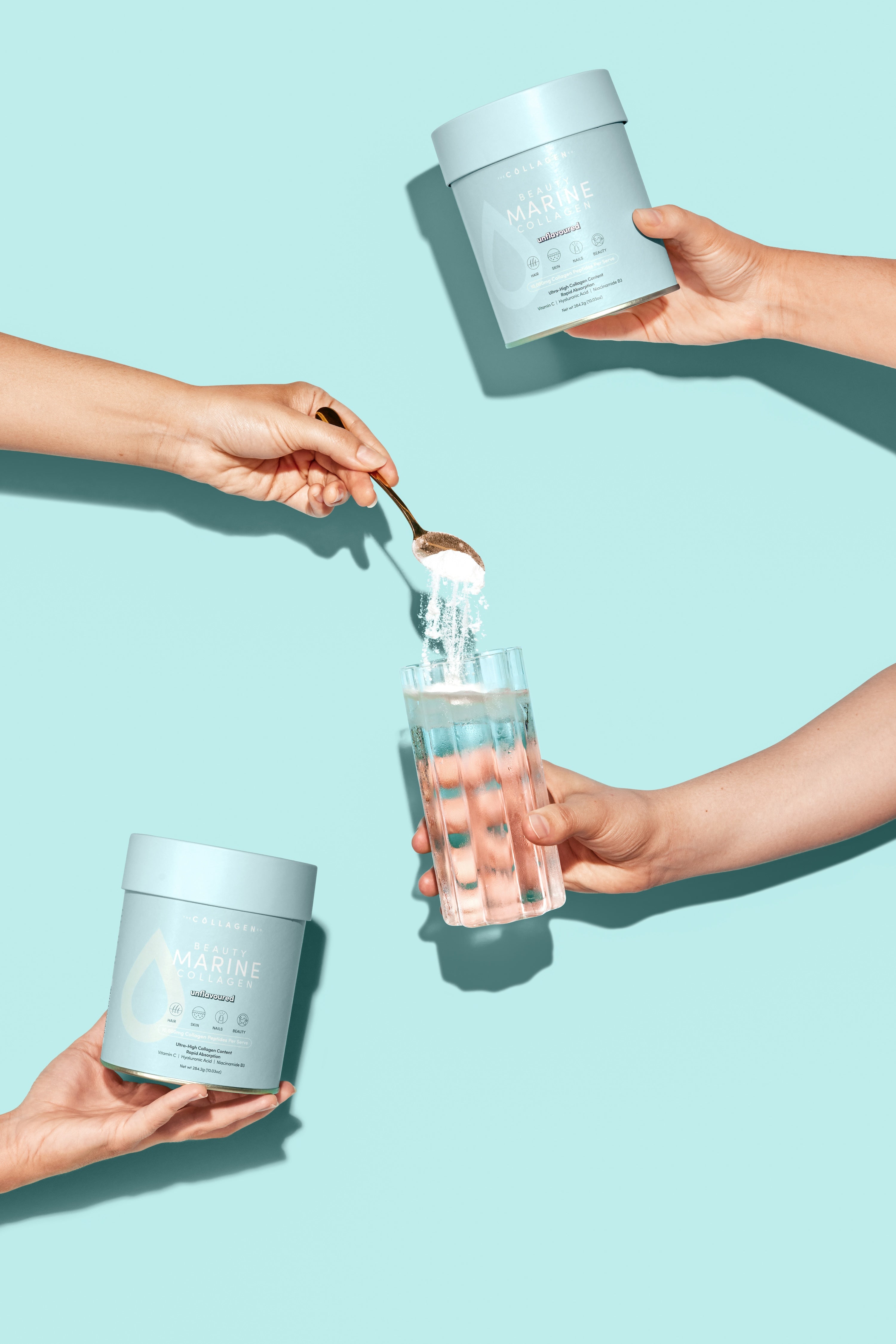 Hands holding collagen containers and a glass. A spoon scoops collagen powder from a jar into the glass. Pastel blue background.