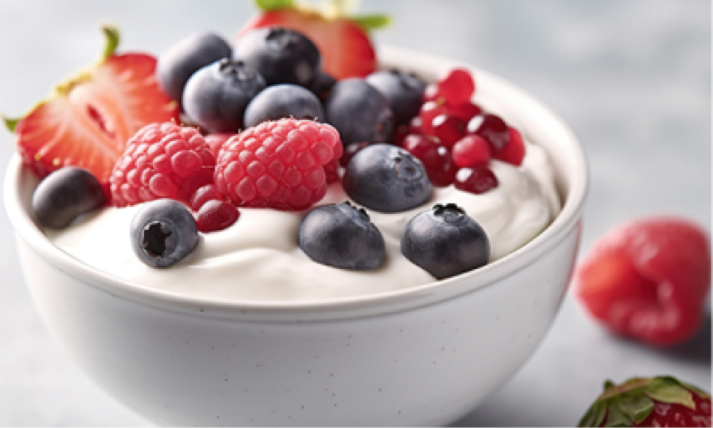 A bowl of creamy yogurt topped with fresh blueberries, raspberries, strawberries, and pomegranate seeds, ideal for beauty and wellness.
