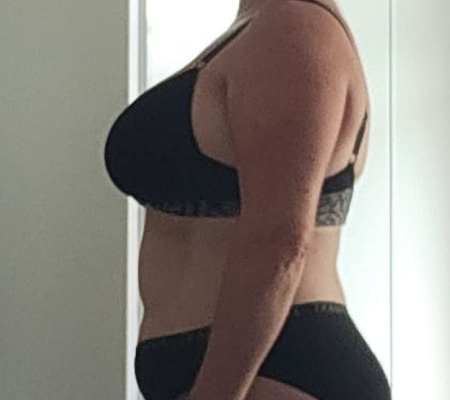 Side profile of a person in black underwear standing indoors, showcasing body transformation. Focus on wellness and health journey.