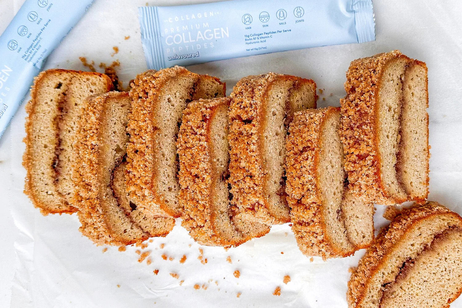 Sliced crumb cake on parchment with collagen supplement packets in the background. Perfect blend of beauty and health.