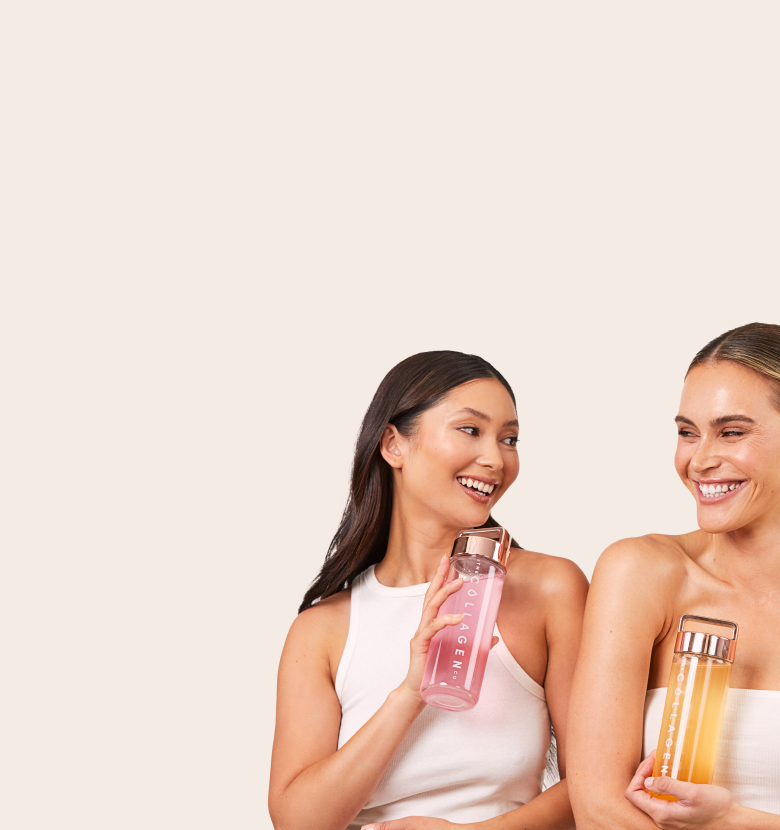 Two women smiling, holding bottles of collagen supplements; one bottle is pink, the other is orange. They wear white tops against a beige background.