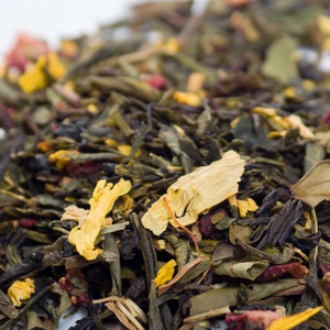 Close-up of loose herbal tea blend with green leaves, yellow petals, and red fruit pieces.