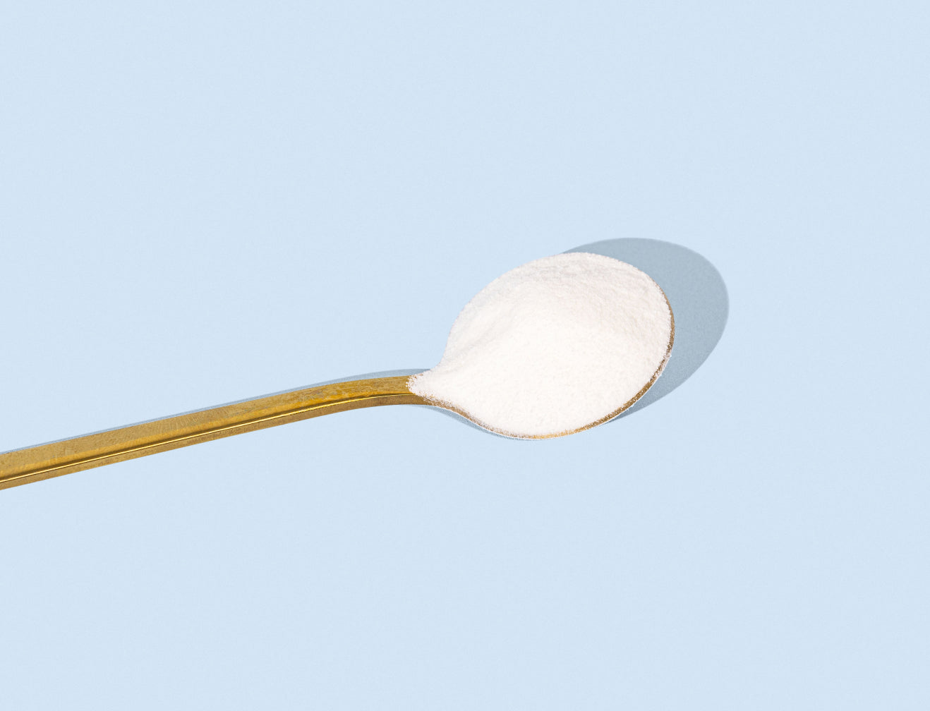 Wooden spoon with white collagen powder against a light blue background, highlighting beauty and wellness supplements.